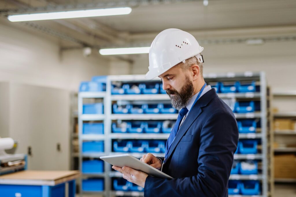 Manager in suit controlling goods in a warehouse.